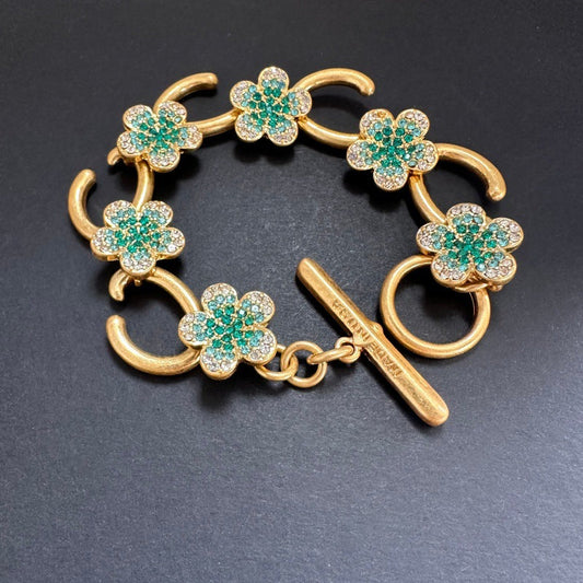 Gold-tone bracelet with green flower charms, pave stones, and bar toggle clasp