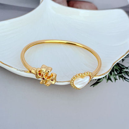Gold-tone open bracelet showing heart clasp and mother-of-pearl heart charm