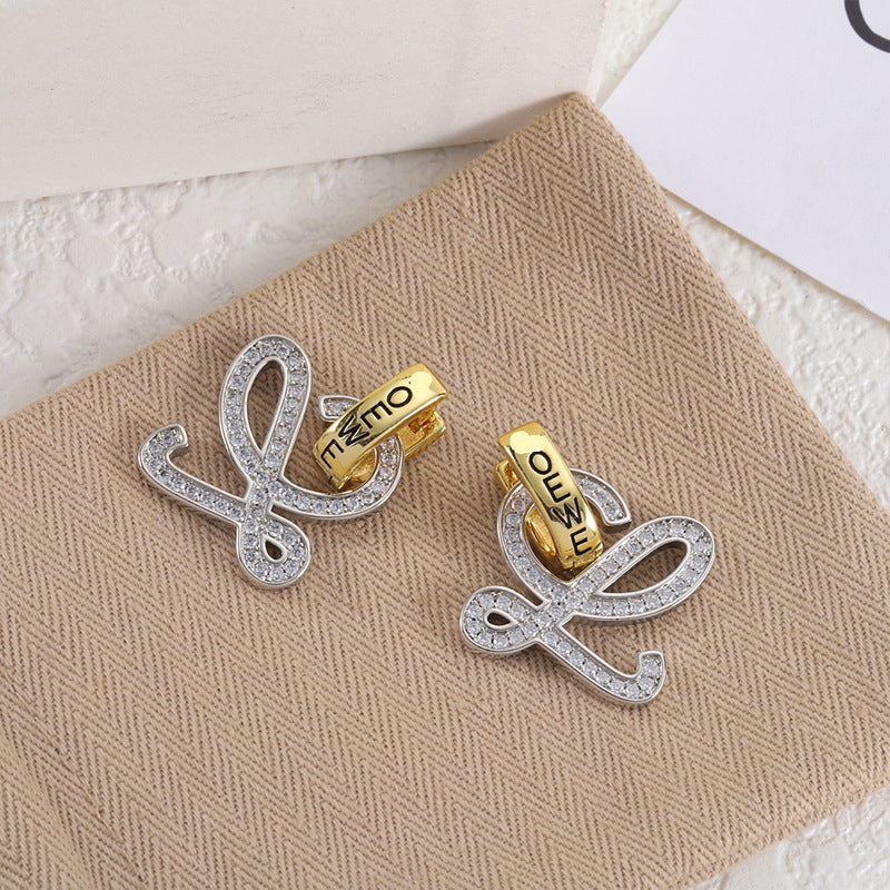 Gold and silver logo stud earrings with openwork heart-shaped outline and clear stones