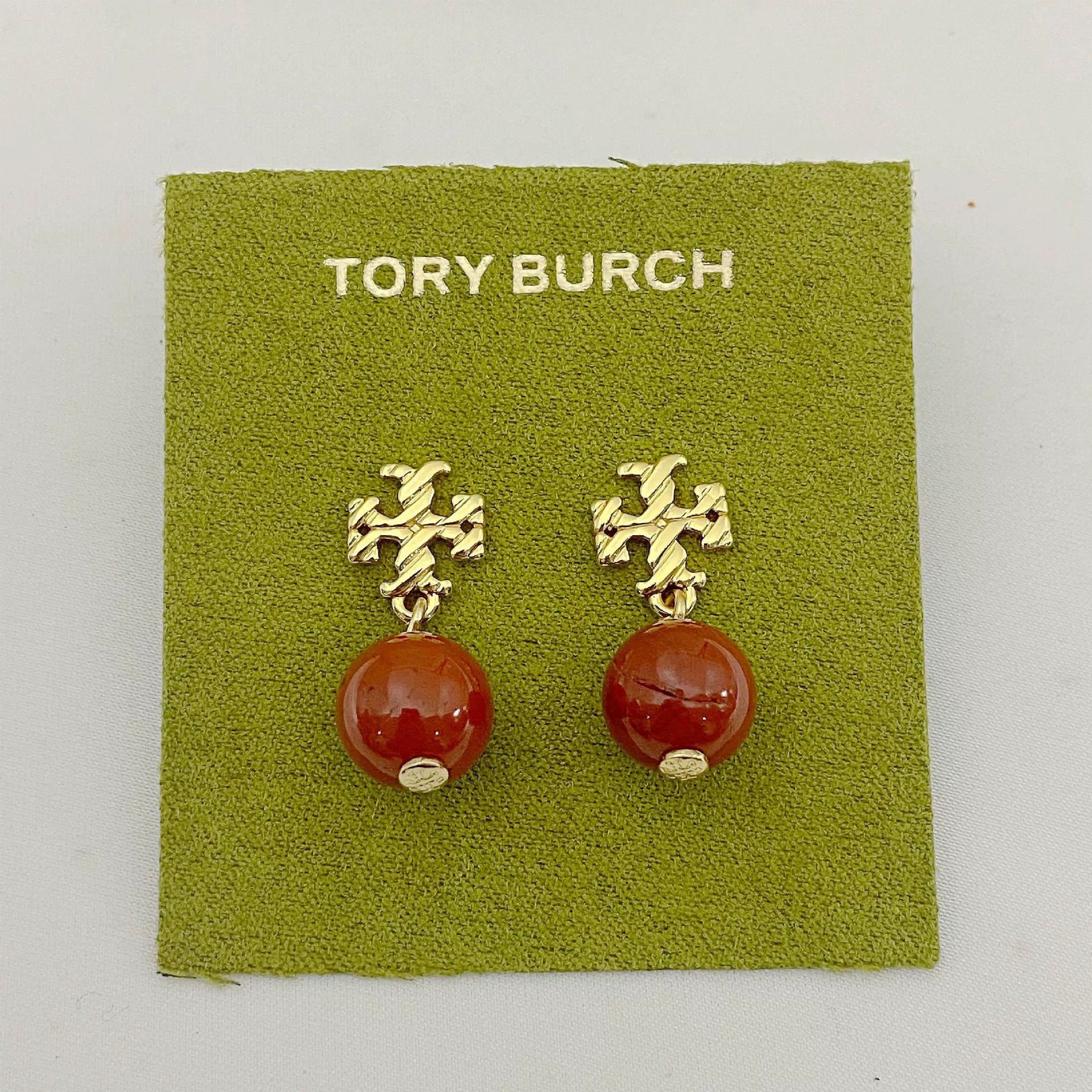 Gold-tone agate pendant earrings with round orange-red stones and leaf-like top