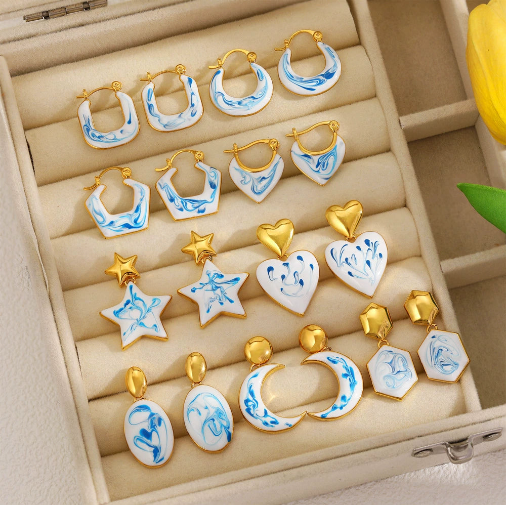 Jewelry tray of blue marble gold-tone earrings, including hoops, stars, and drops