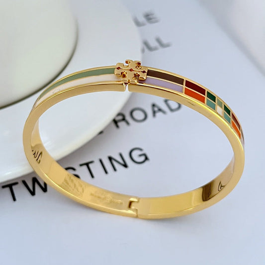 Gold-tone metal bangle featuring multicolor enamel plaid strip and small clasp at top