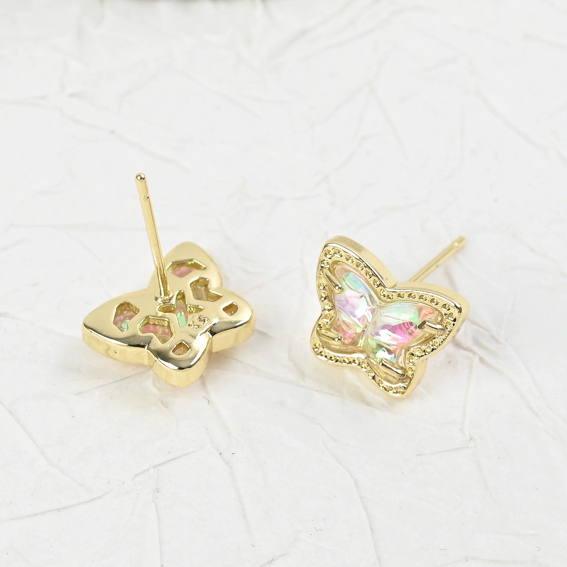 Gold butterfly stud earrings with iridescent multi-color stones, side view