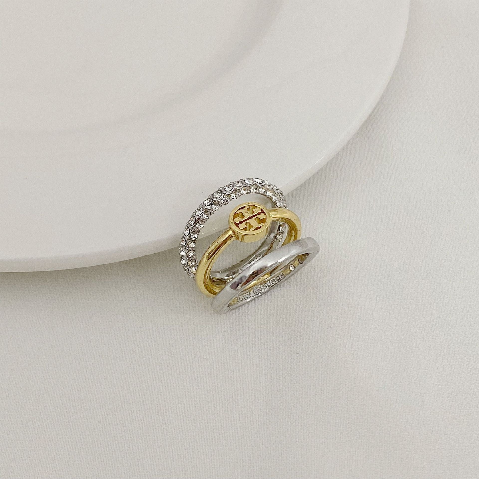Gold-tone and silver-tone three-band ring with rhinestone bezel and logo medallion