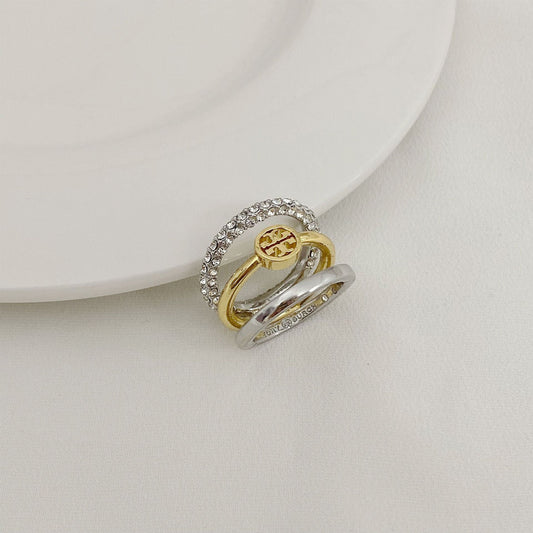 Gold-tone and silver-tone three-band ring with rhinestone bezel and logo medallion