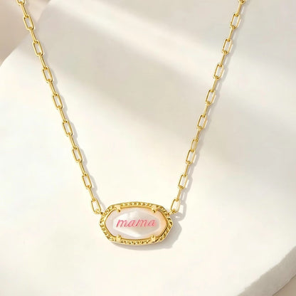 Gold oval pendant necklace with “mama” script and textured edge on curb chain