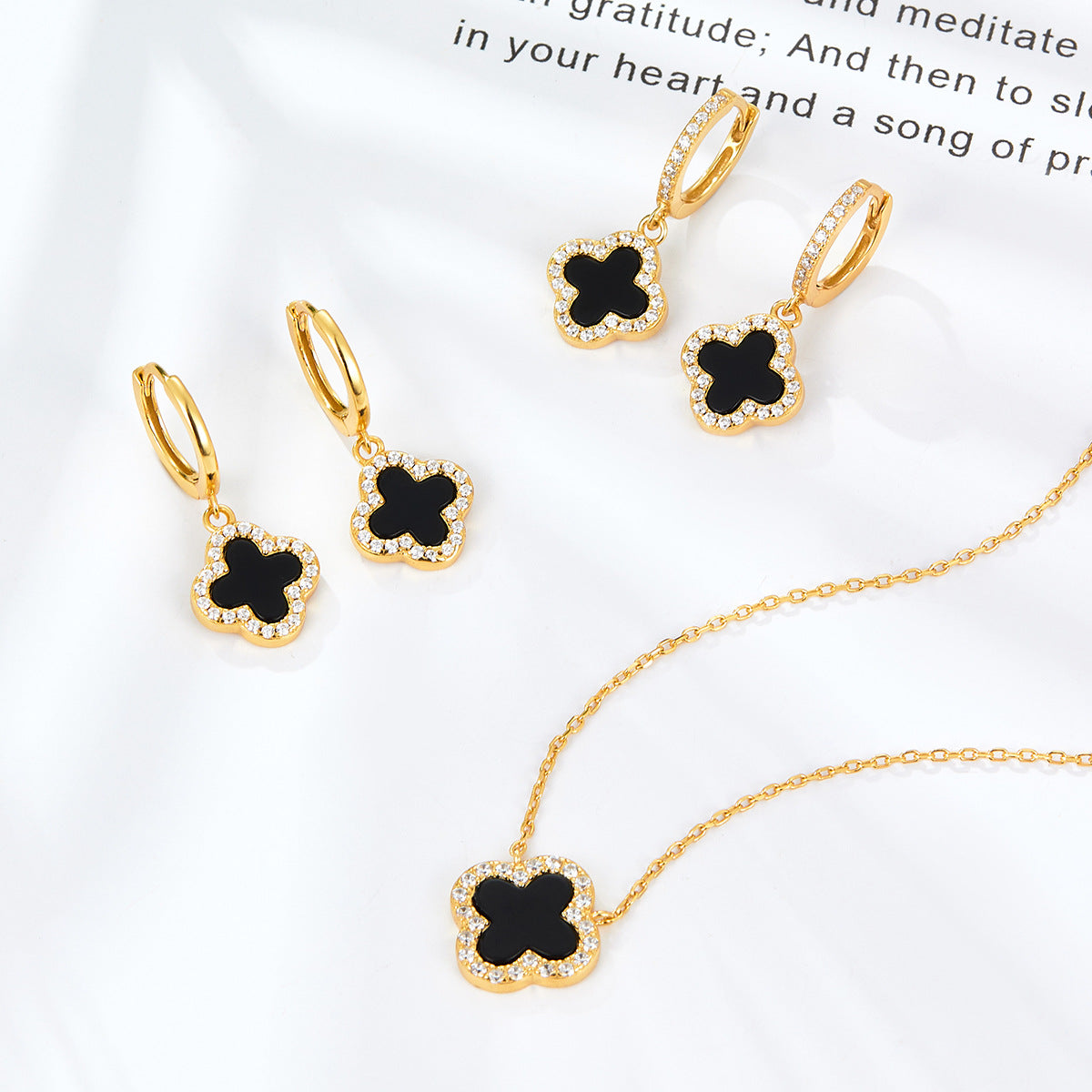 Gold-tone four-leaf clover pendant necklace with black onyx center and clear stones