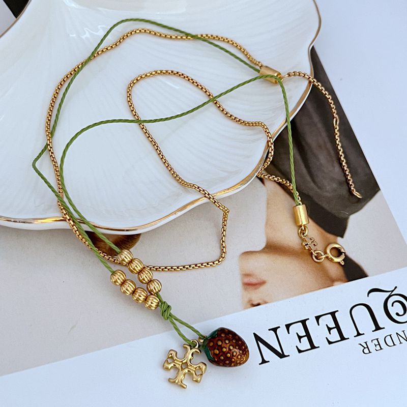 Gold-tone beaded double necklace with red berry pendant and small cross charm, green cord
