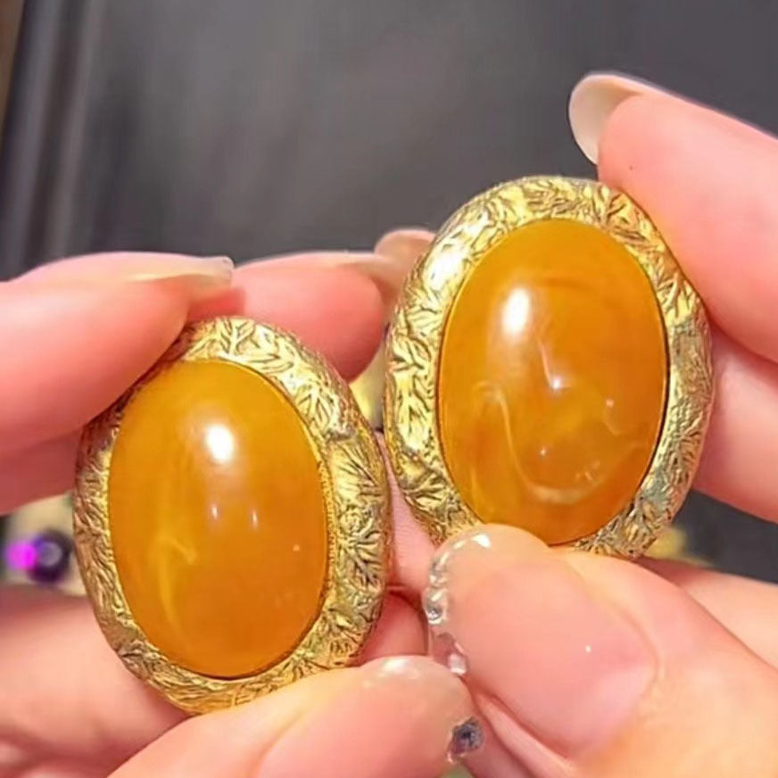 Oval yellow glass cabochon stud earrings with ornate gold-tone bezel, close-up