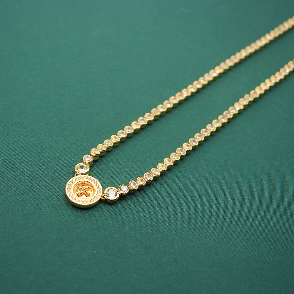 Gold-tone beaded necklace with round coin clover charm and small crystal accents