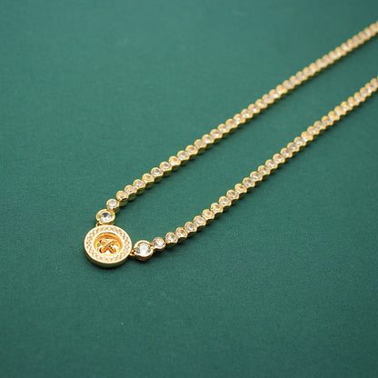 Gold-tone beaded necklace with round coin clover charm and small crystal accents