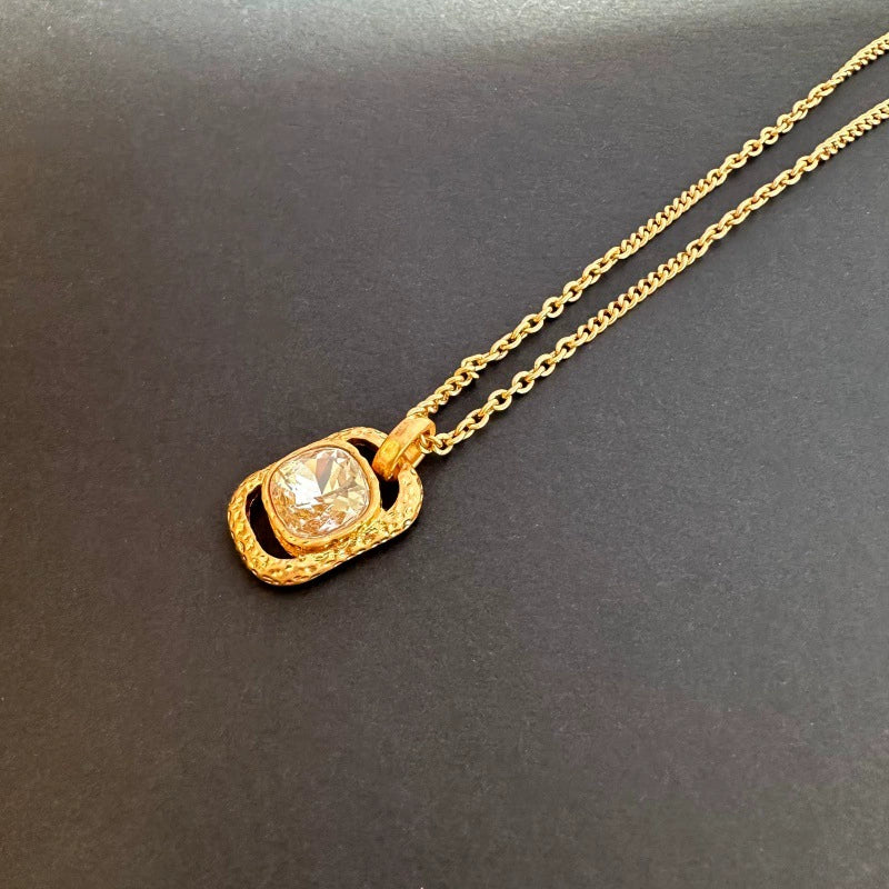 Gold-tone hammered square pendant necklace with clear faceted gemstone on chain