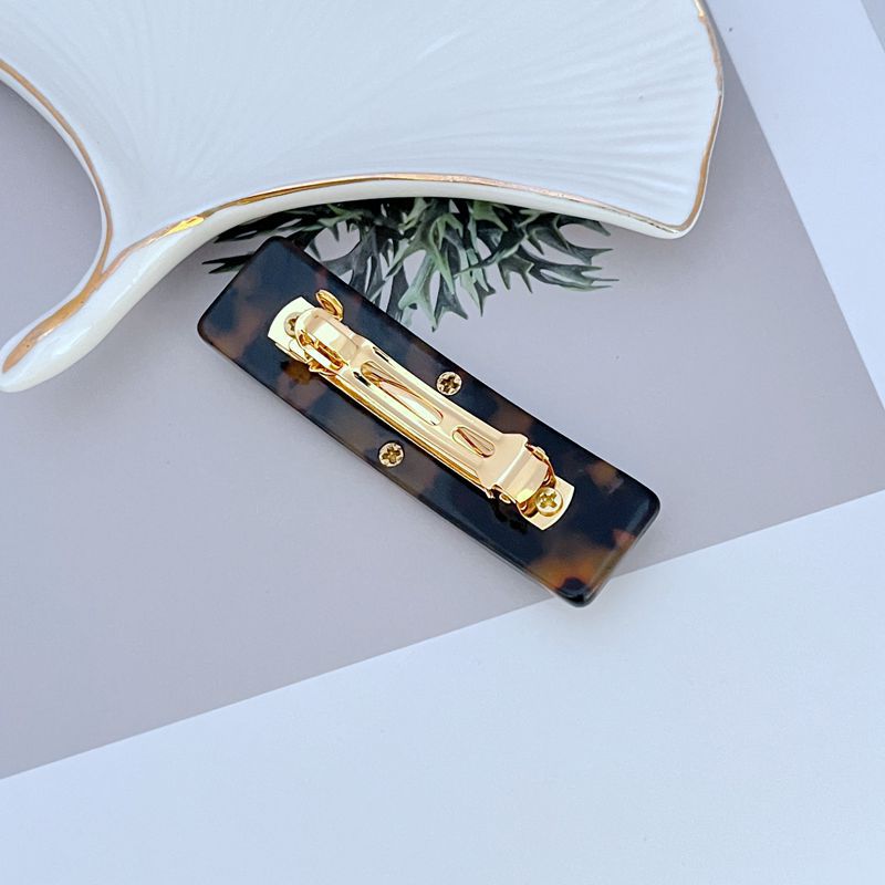 Dark tortoise acrylic hair clip with gold-tone clasp and logo front