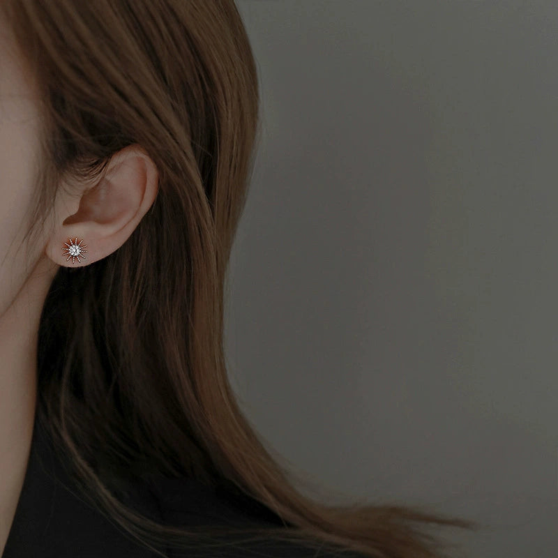 Starburst diamond stud earring in rose gold tone, worn on ear