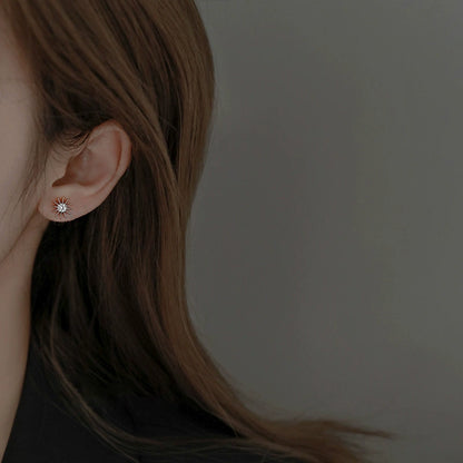 Starburst diamond stud earring in rose gold tone, worn on ear
