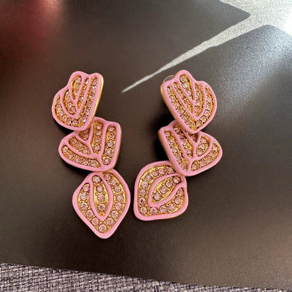 Gold-plated leaf pendant earrings with pink enamel hearts and crystal stone detailing
