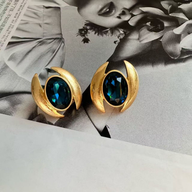 Gold-tone oval crystal stud earrings with dark blue faceted stones