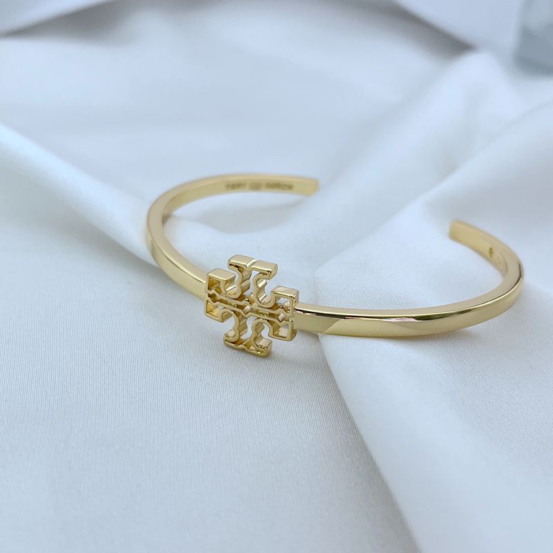 Gold tone openwork square logo bangle, side view of smooth cuff and emblem