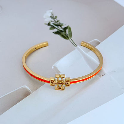 Open gold-tone bangle with cutout logo charm and orange enamel inner stripe