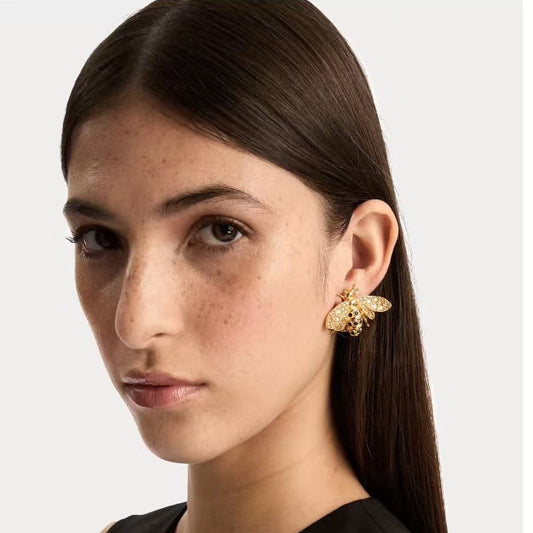 Bee crystal earrings worn on model ear, gold-tone insect design with wings