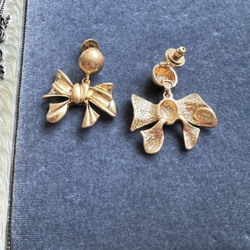Gold-tone vintage metal bow earrings shown from front and back, with round ball posts.