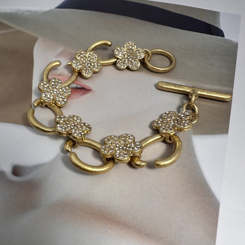 Gold-tone bracelet with clear pave flower charms and heart toggle clasp