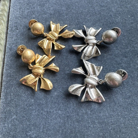 Pair of vintage metal bow earrings: gold-tone and silver-tone, round ball stud tops.