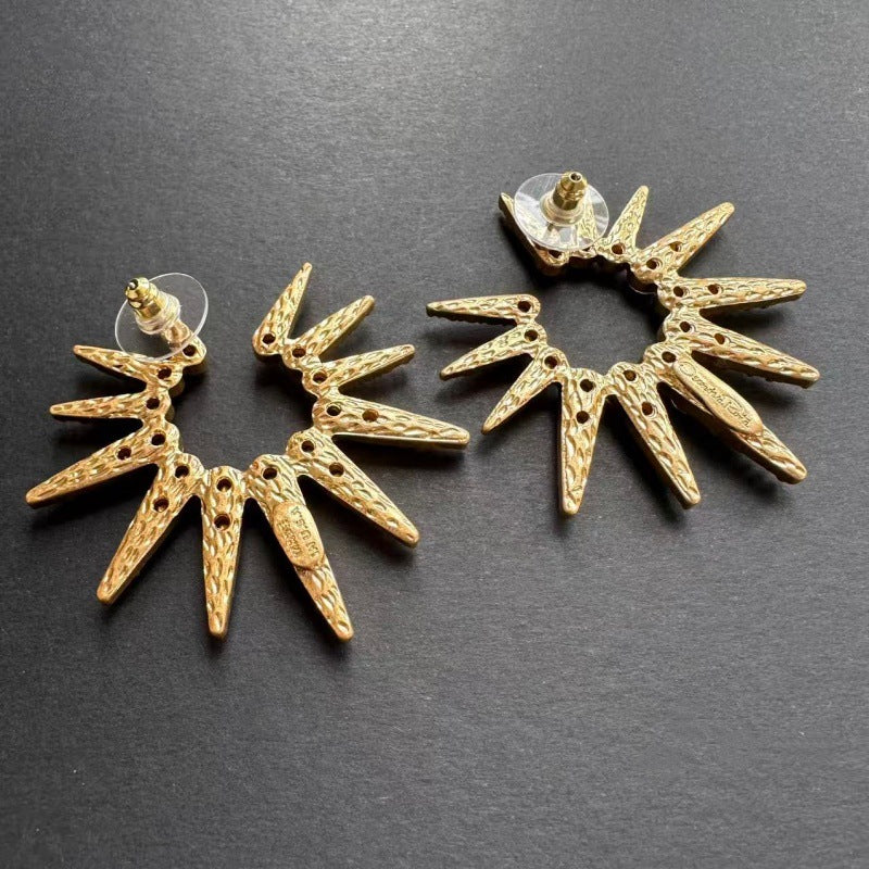 Gold-tone starburst stud earrings with faceted clear stones and circular backing
