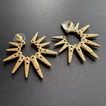 Gold-tone starburst stud earrings with faceted clear stones and circular backing