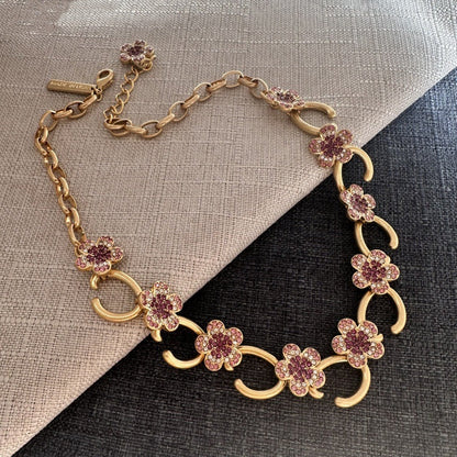 Gold-plated floral pendant necklace with purple rhinestone clover charms and curved links