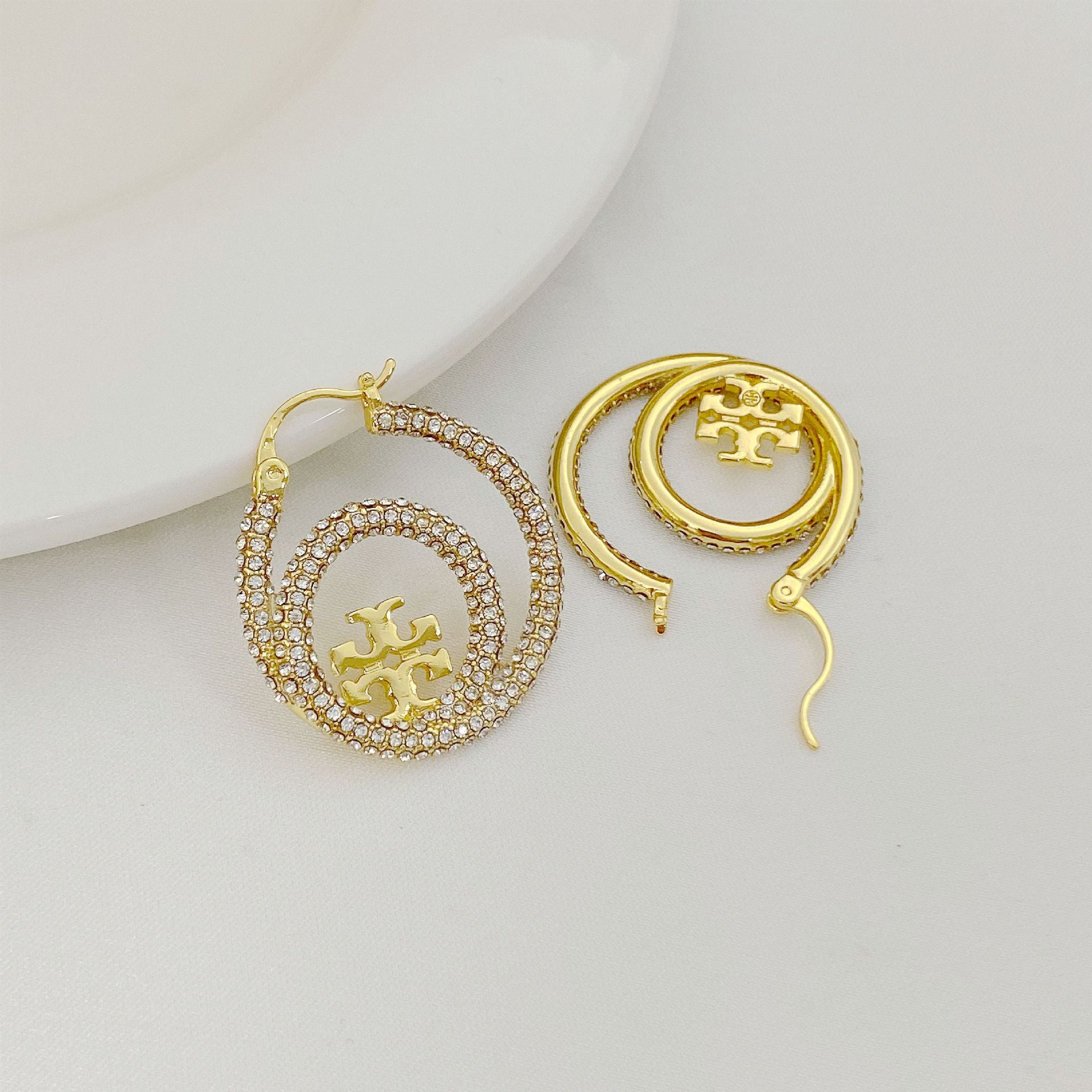 Gold hoop earrings with Tory Burch logo medallion and diamond pavé hoop detail