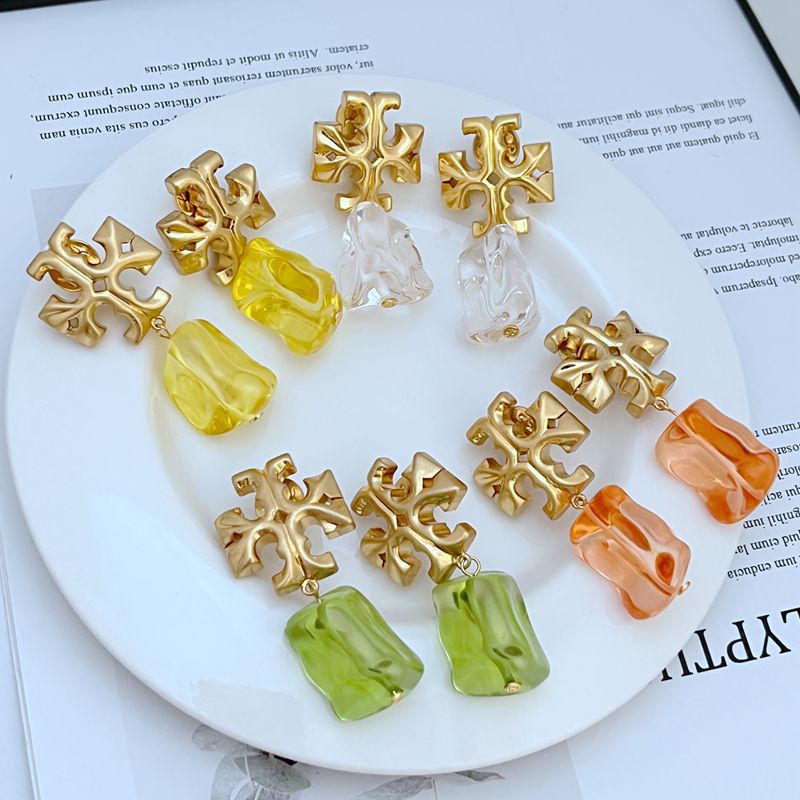 Gold-tone logo pendant earrings with multicolor acrylic drop charms (clear, yellow, orange)