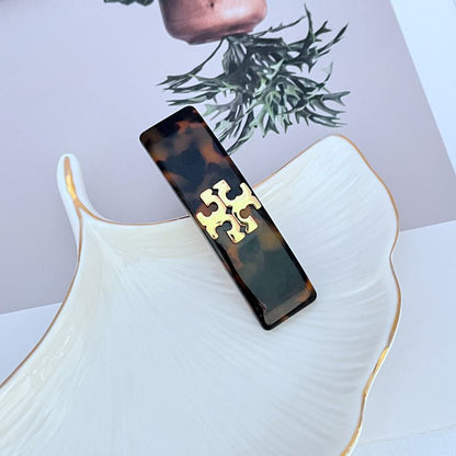 Dark tortoise acrylic logo hair clip with gold interlocking T emblem