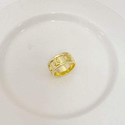 Gold band ring with engraved letter motif and textured side panels