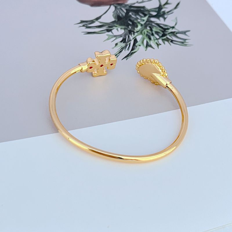 Gold-tone open bangle with heart-shaped toggle charm and mother-of-pearl heart