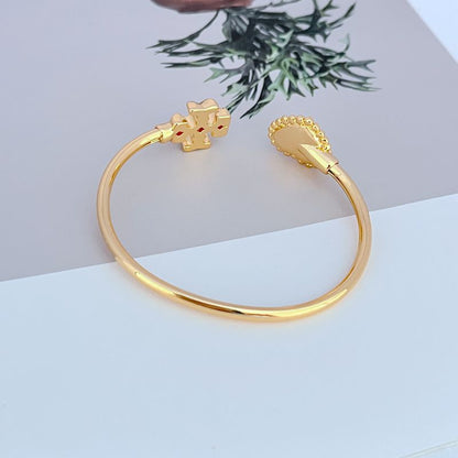 Gold-tone open bangle with heart-shaped toggle charm and mother-of-pearl heart