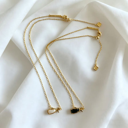 Gold-tone layered charm necklace with multiple thin chains and small heart pendants