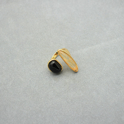 Asymmetrical gold open ring with black oval stone and translucent light centerpiece.