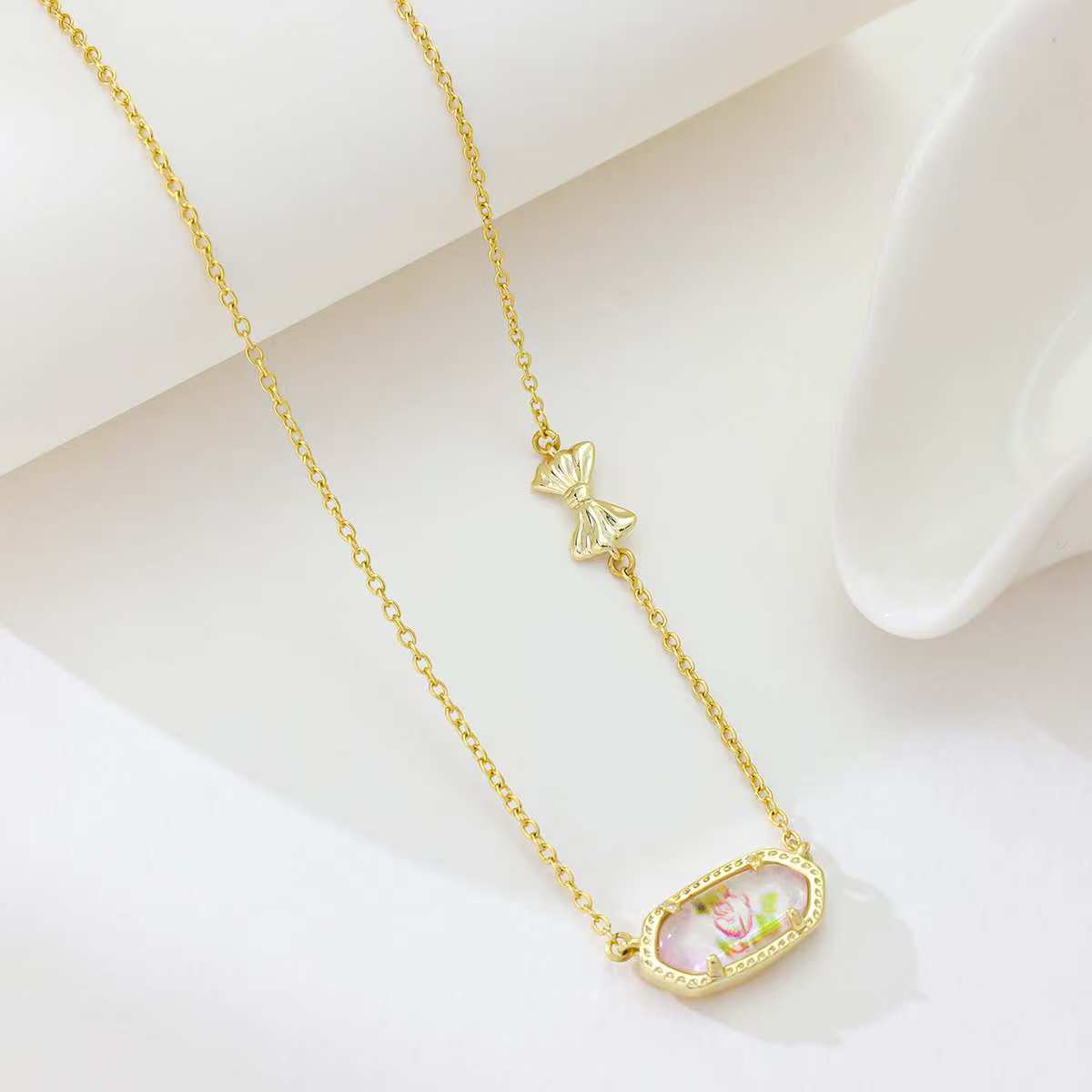 Gold butterfly pendant necklace with oval pink enamel pendant and butterfly charm