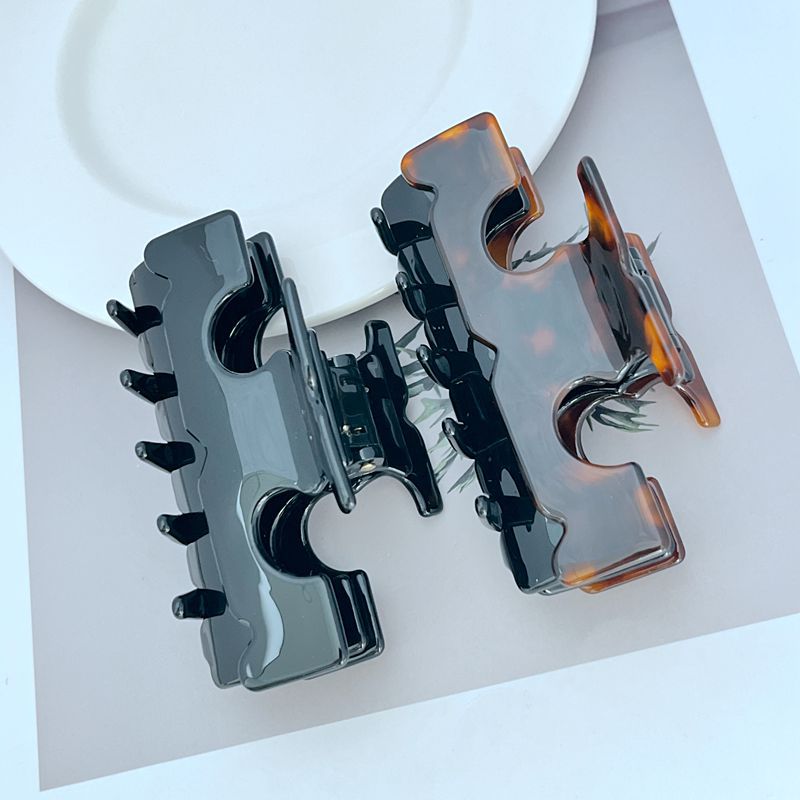 Two-tone T-shaped hair clip with dark prongs and amber side accents