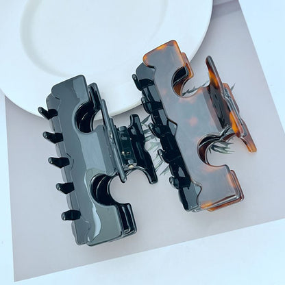 Two-tone T-shaped hair clip with dark prongs and amber side accents