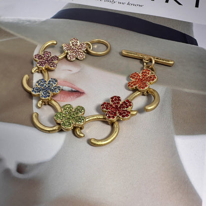 Gold-tone bracelet with multicolor flower charms and pave stones, toggle clasp close-up