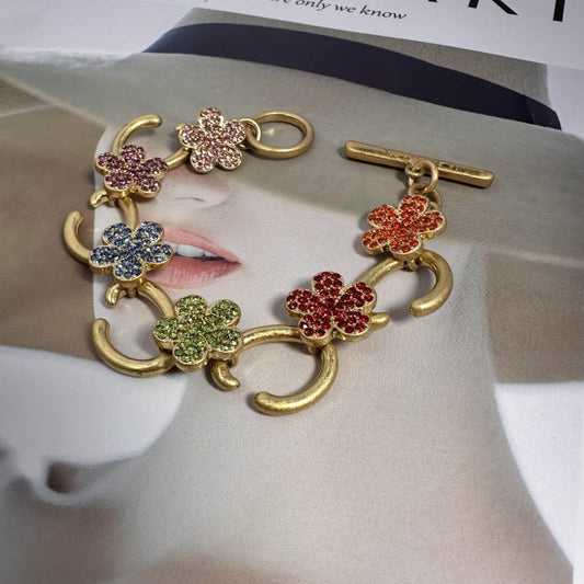 Gold-tone bracelet with multicolor flower charms and pave stones, toggle clasp close-up