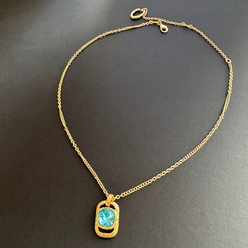 Gold chain square pendant necklace with hammered texture and blue faceted gem