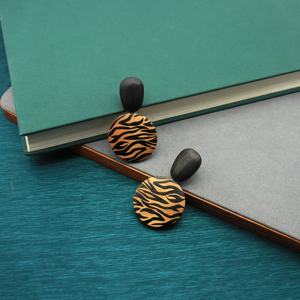 Handcrafted wooden earrings with zebra-pattern round discs and black caps