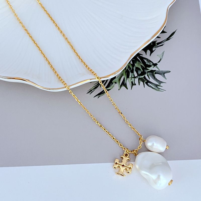 Gold necklace with two baroque pearl charms and ornate logo pendant, double-layer chain