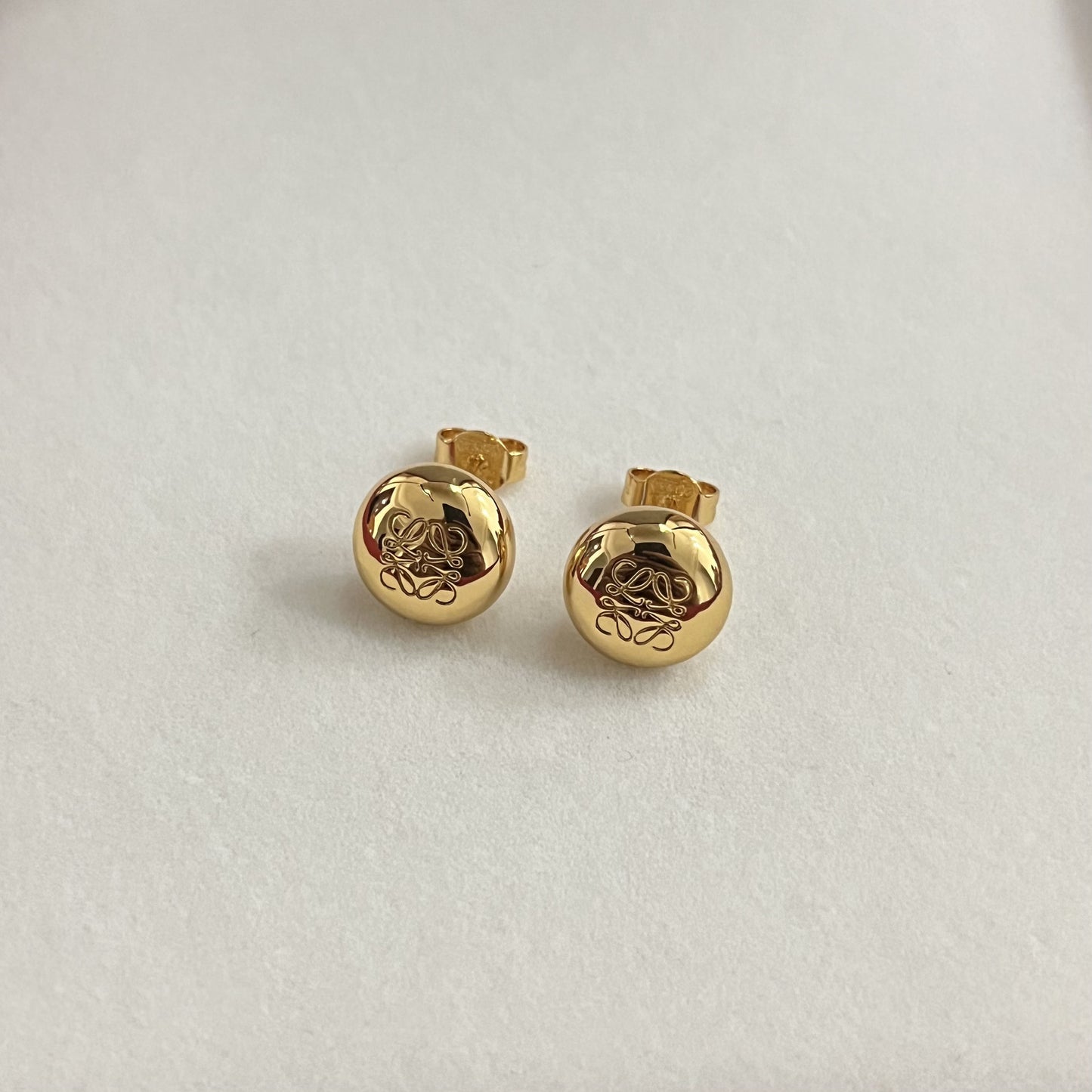 Gold round stud earrings with smooth bean shape and engraved knot design, stud backs