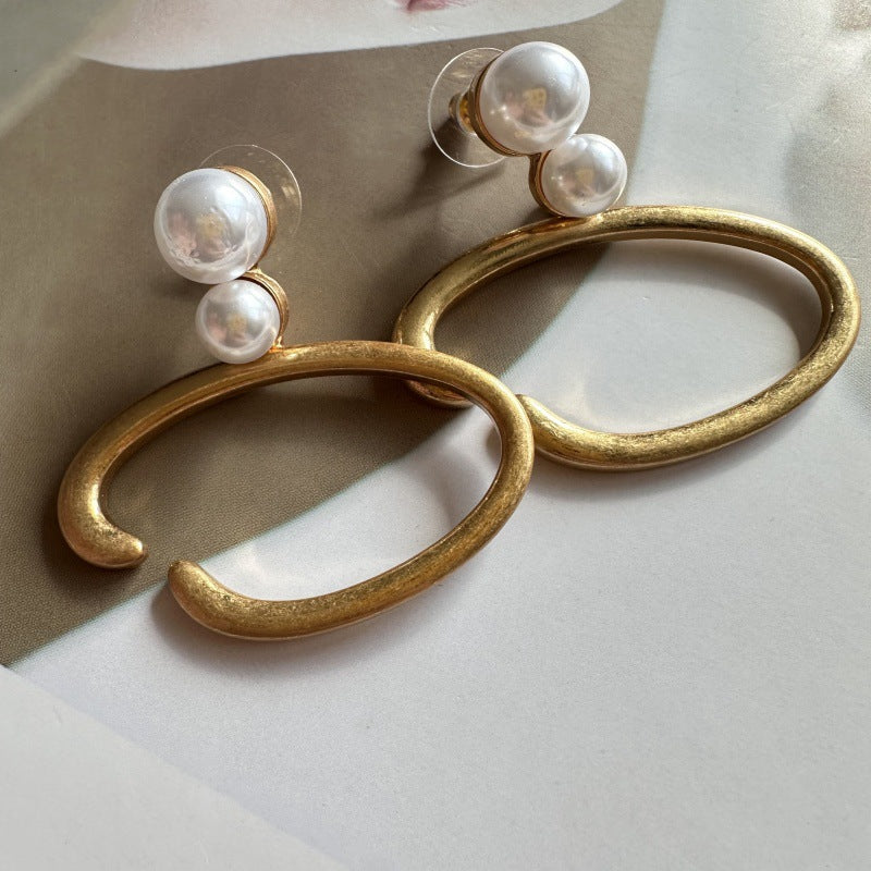 Gold-tone O-ring hoop earrings with two white pearls at the top bar