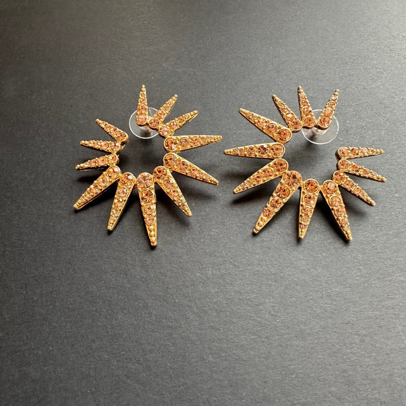 Champagne-gold starburst stud earrings with faceted clear stones