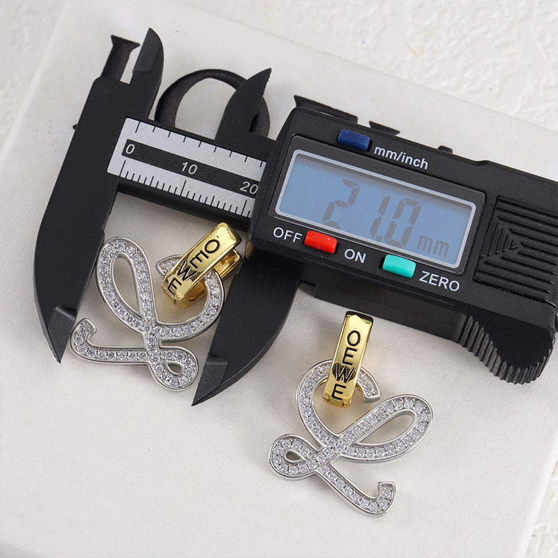 Gold and silver logo stud earrings with openwork outline and clear stones; caliper measurement